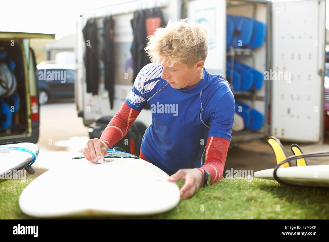 Male surfer waxing surfboard Stock Photo
