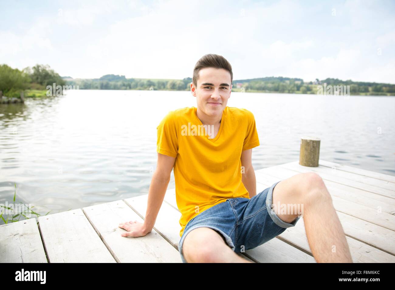 Portrait of young man sitting on jetty Stock Photo