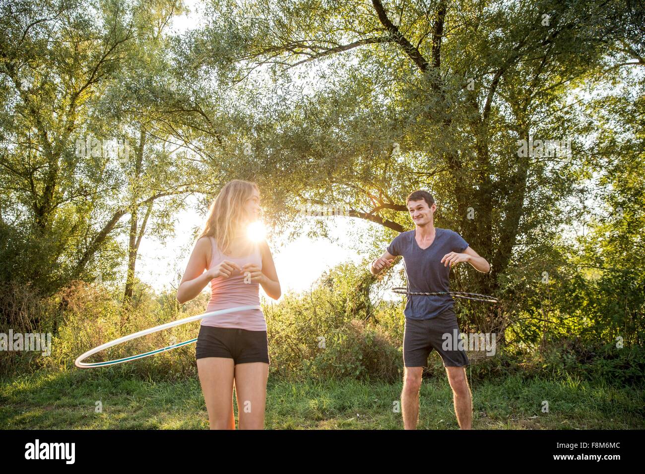 Young couple in rural environment, using hula hoops Stock Photo