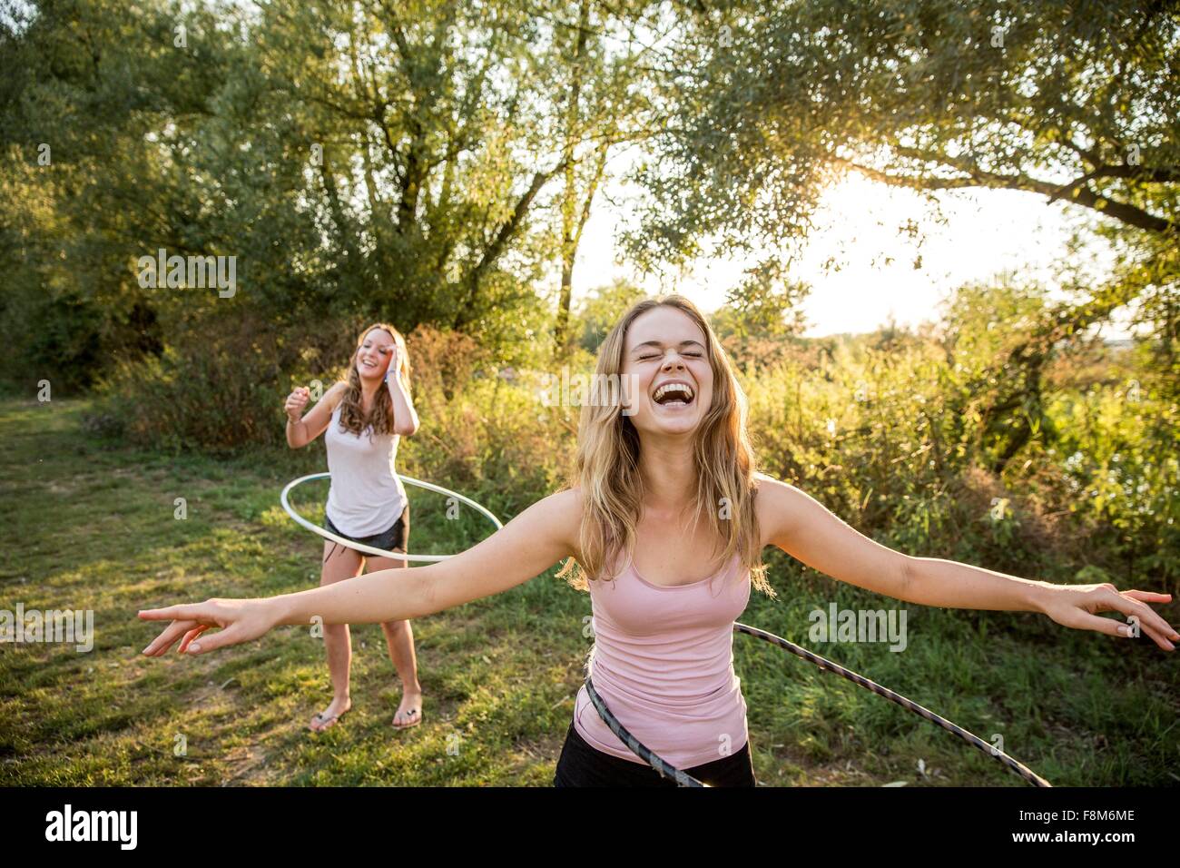Two young girls in rural environment, fooling around, using hula hoops, Stock Photo