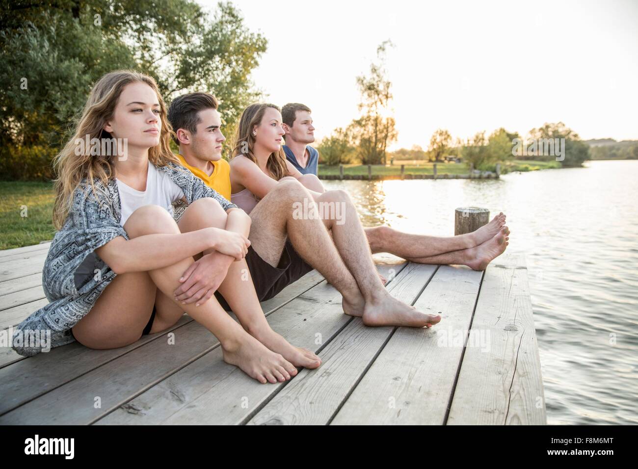 Group of friends sitting on jetty, relaxing Stock Photo