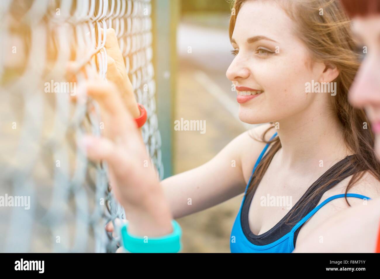 Young women standing beside fence Stock Photo
