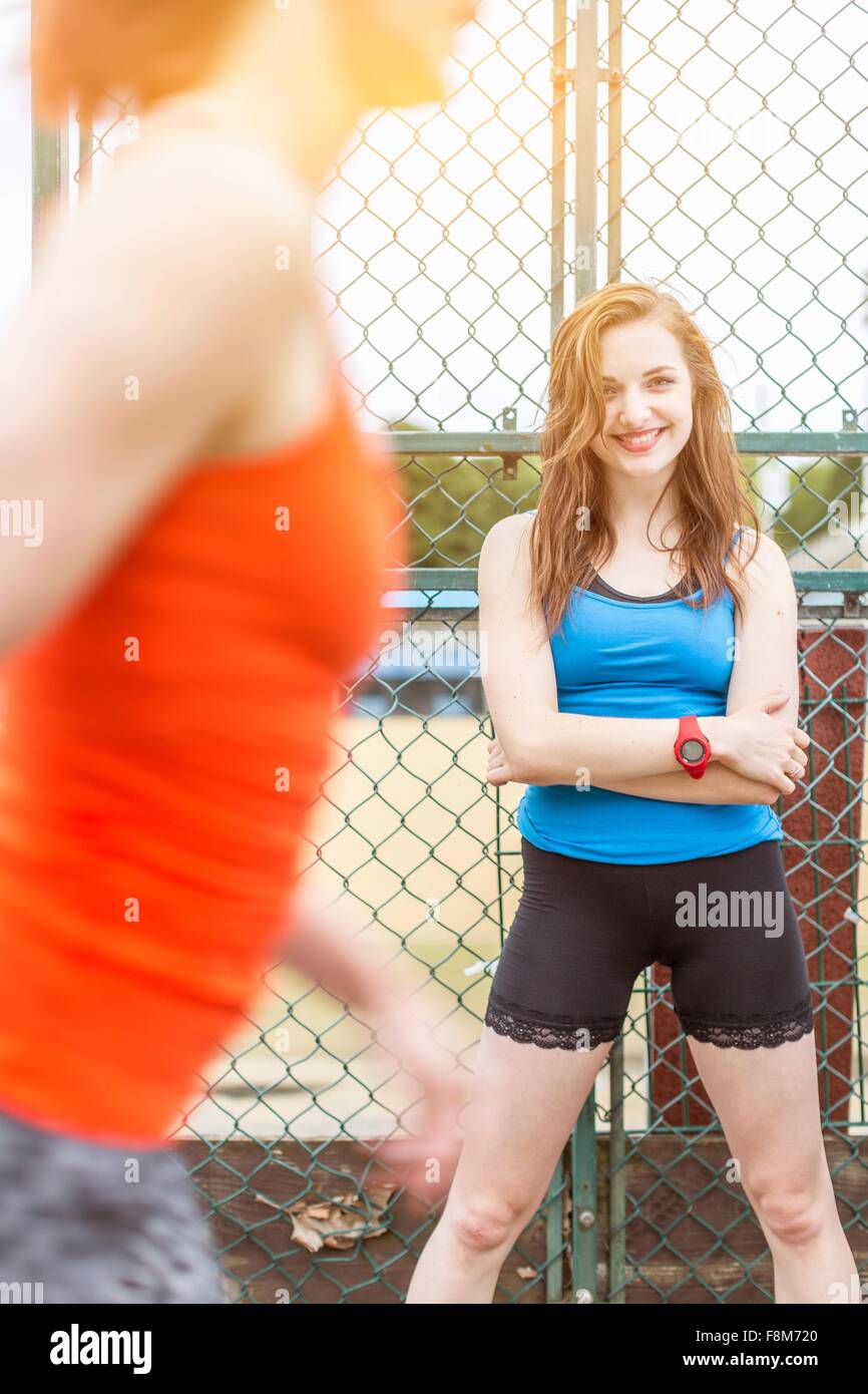 Runner passing young woman standing beside sports ground, London, UK Stock Photo