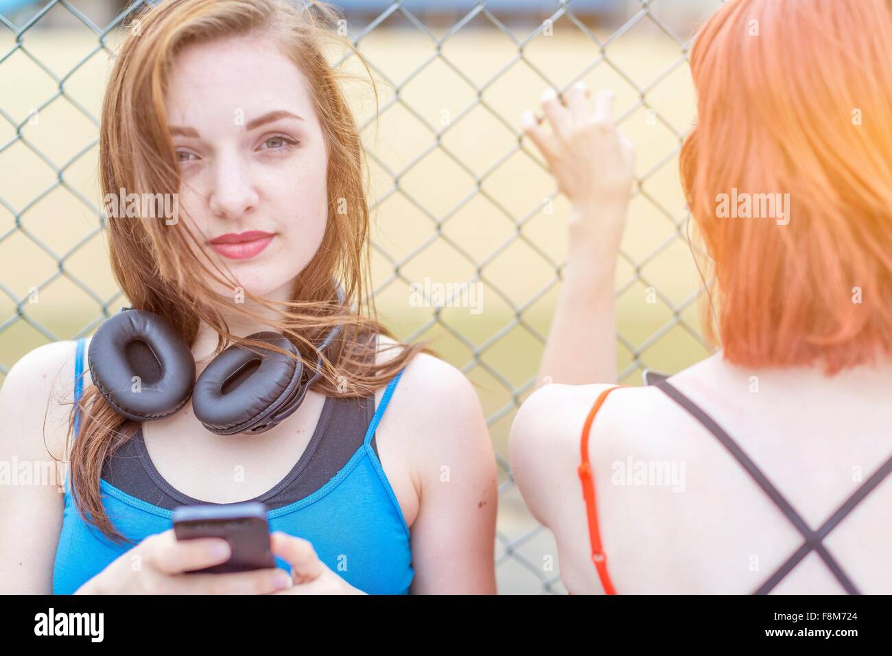 Young woman using smartphone beside fence Stock Photo