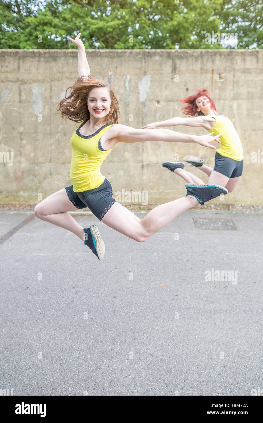 Young women jumping in front of concrete wall Stock Photo
