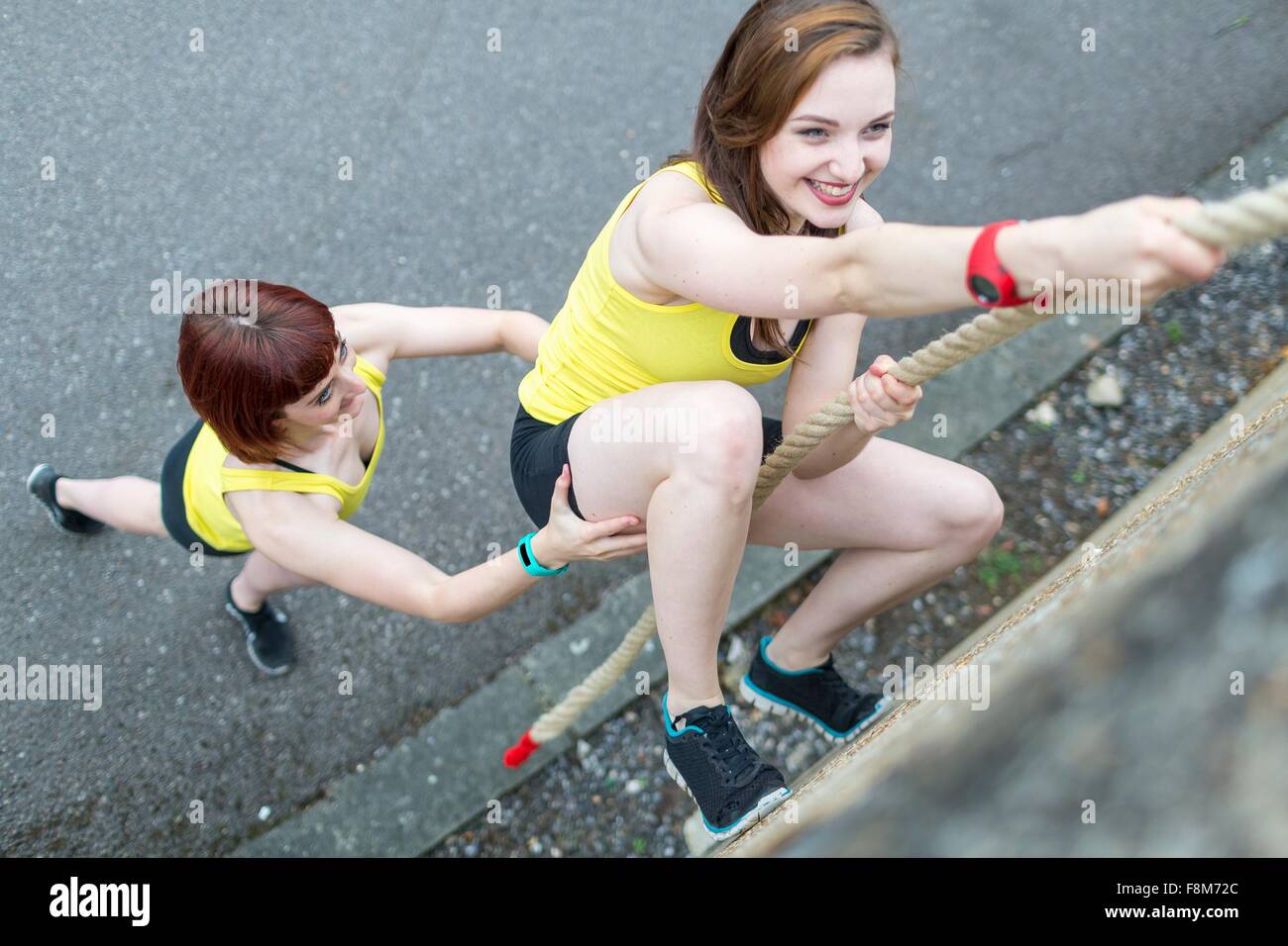Young women climbing over wall with rope Stock Photo