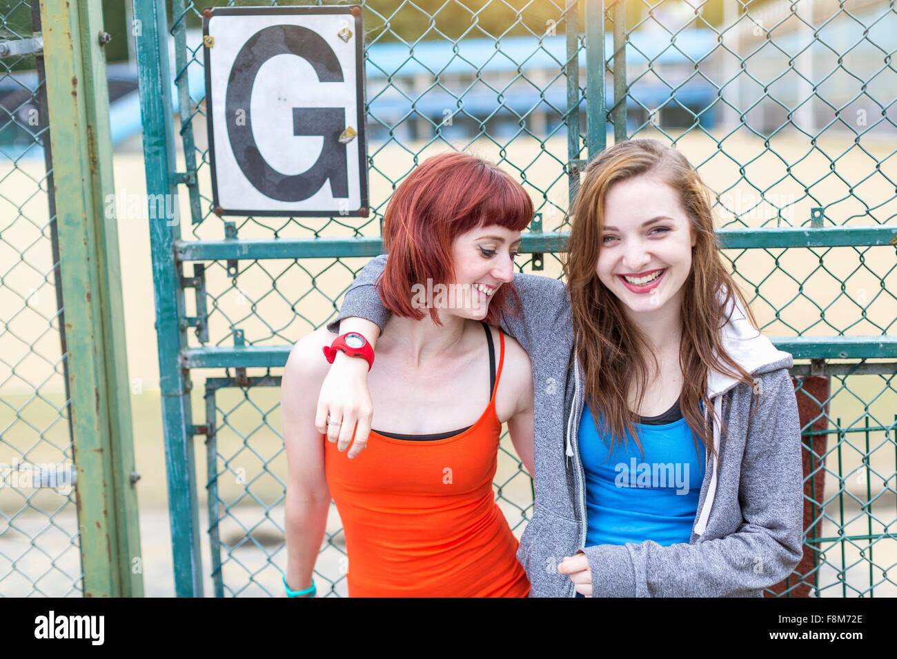 Young women standing beside sports ground, London, UK Stock Photo