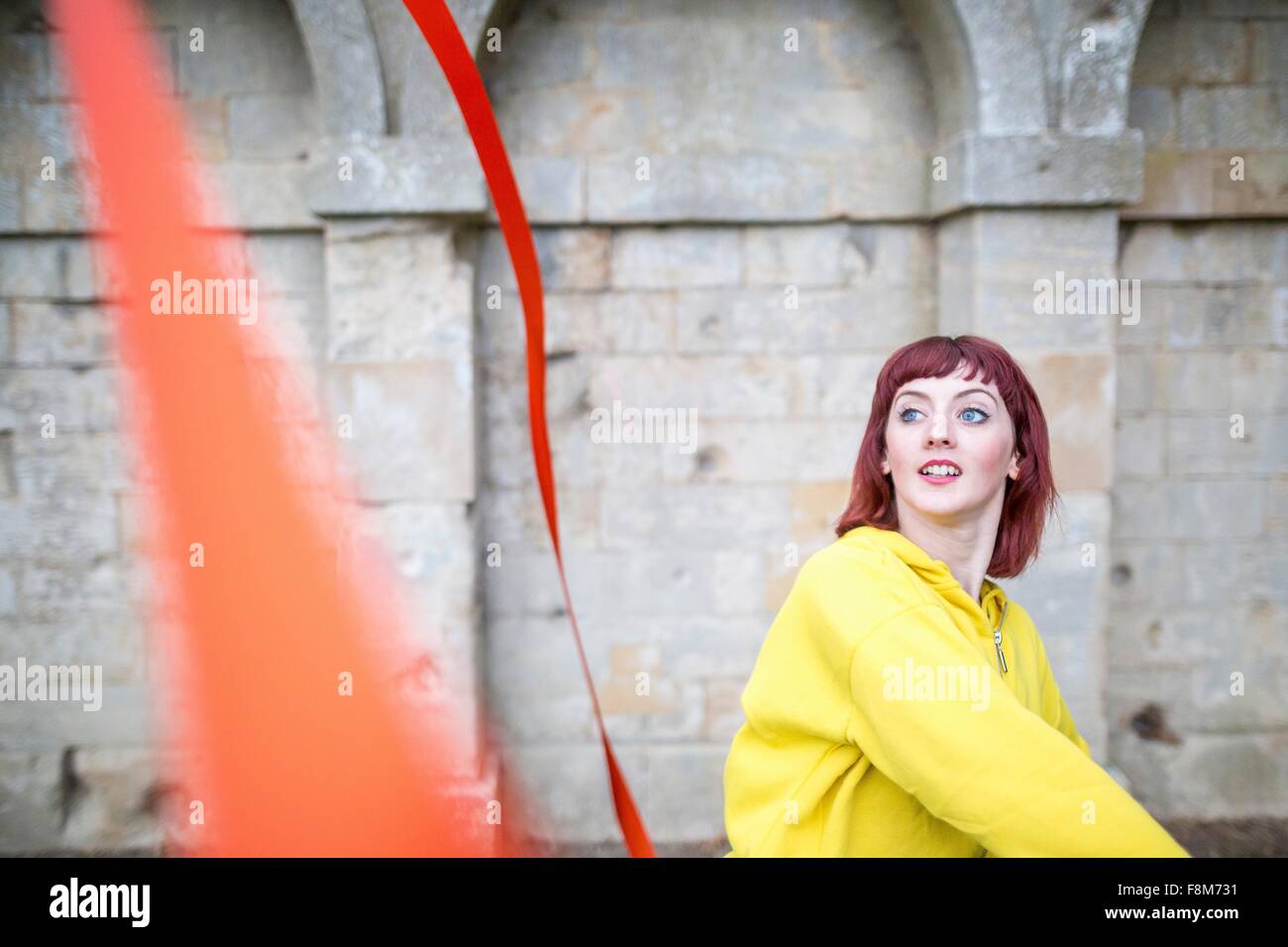 Young woman practising ribbon dance, walled arches in background Stock Photo