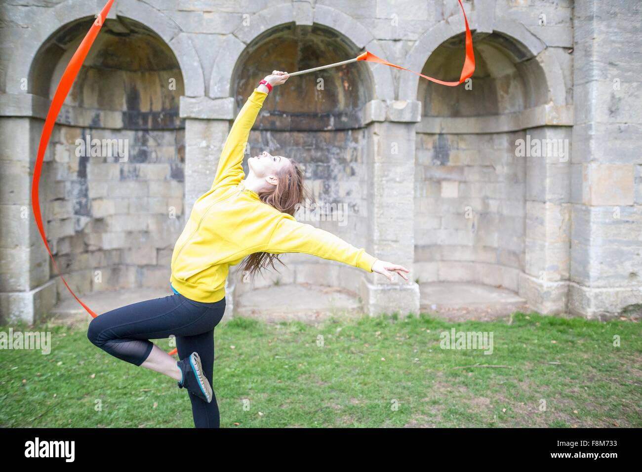 Young woman practising ribbon dance, walled arches in background Stock Photo