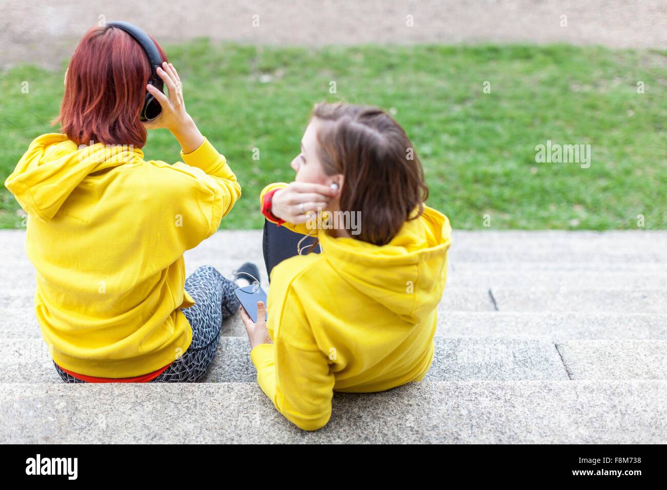 Young women with earphones resting on steps Stock Photo