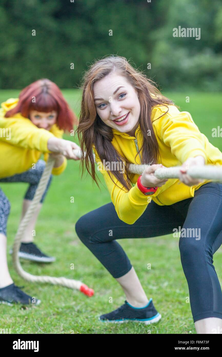 Young women playing tug of war on field Stock Photo