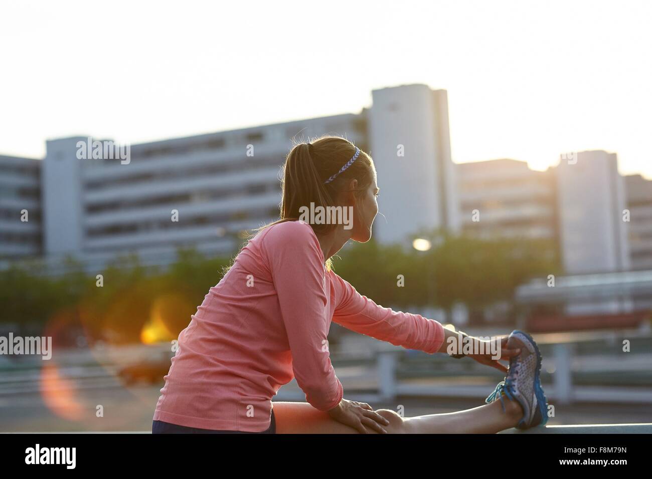 Young female runner touching toes on rooftop Stock Photo