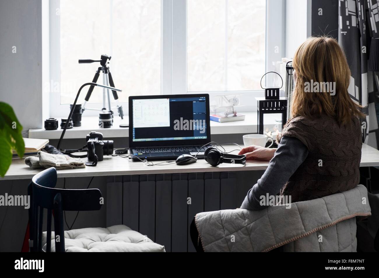 Mid adult woman sitting at desk, using computer, rear view Stock Photo