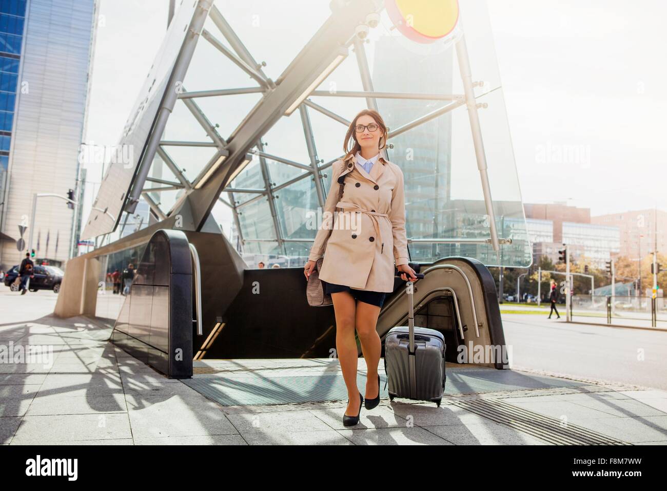 Businesswoman with wheeled suitcase by escalator Stock Photo