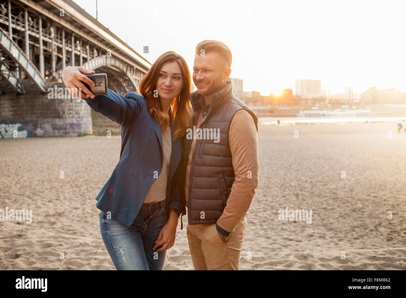 Mid adult couple by bridge taking selfie on phone Stock Photo