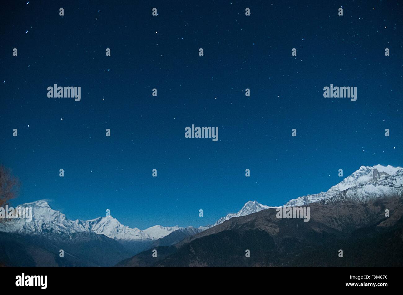 Snow capped mountain range under starry night sky, Nepal Stock Photo