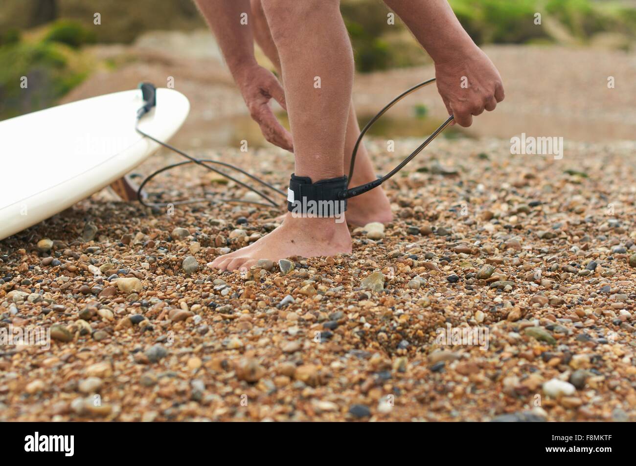 Surfer tying surfboard leash to ankle Stock Photo