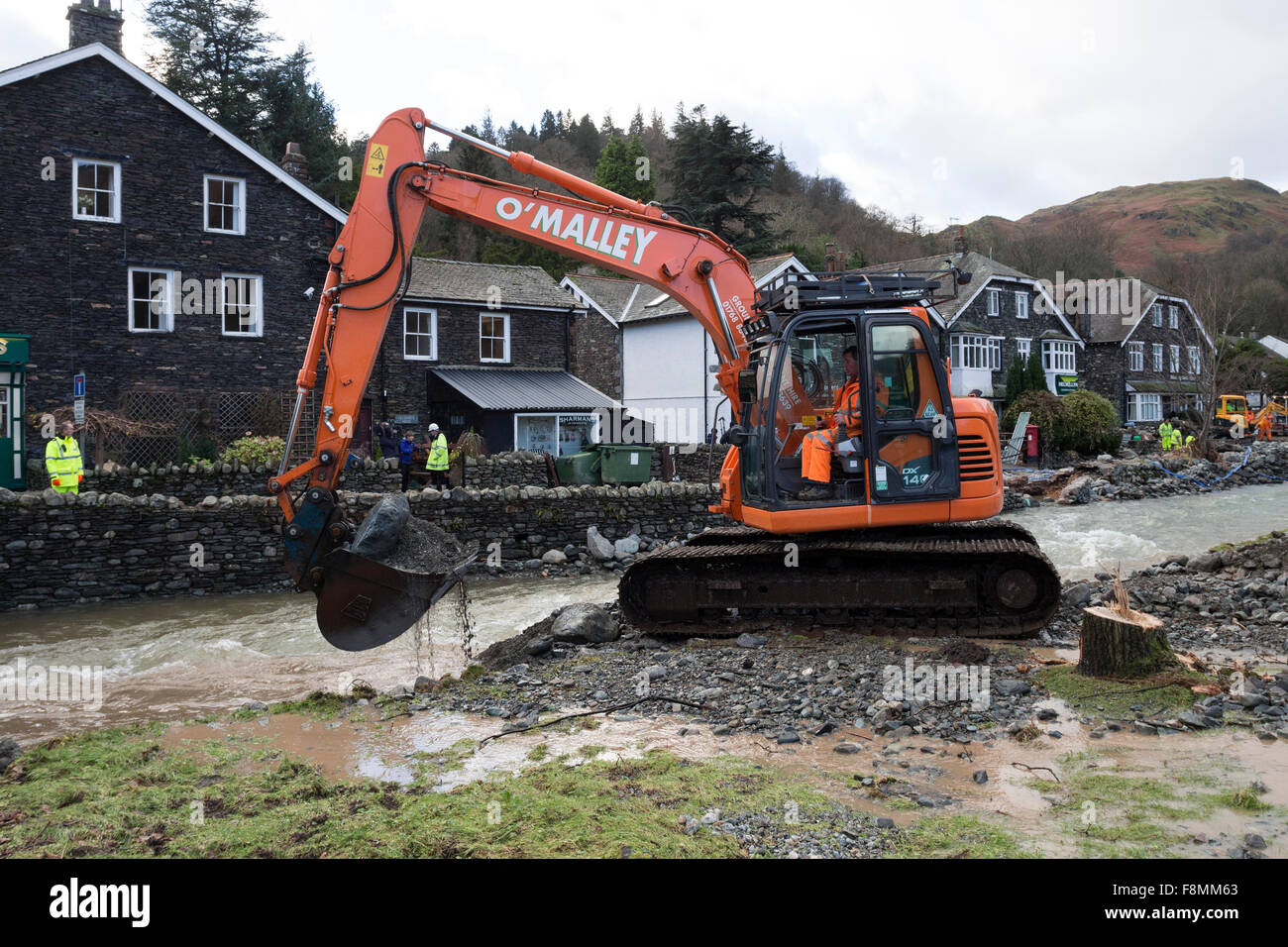 Glenridding, Cumbria, 10th December 2015. UK Weather.  Heavy overnight rain caused more flooding as the river running through the village overflowed again.  Rescue services were called in last night to help people to safety as people's possessions including Christmas decorations were washed down the road. Diggers were used this morning to try and dredge debris from the river in a bid to prevent further flooding.  In nearby Patterdale evidence of the power of the water from Storm Desmond could also be seen where floodwater had burst through the road surface. Credit:  David Forster/Alamy Live Ne Stock Photo