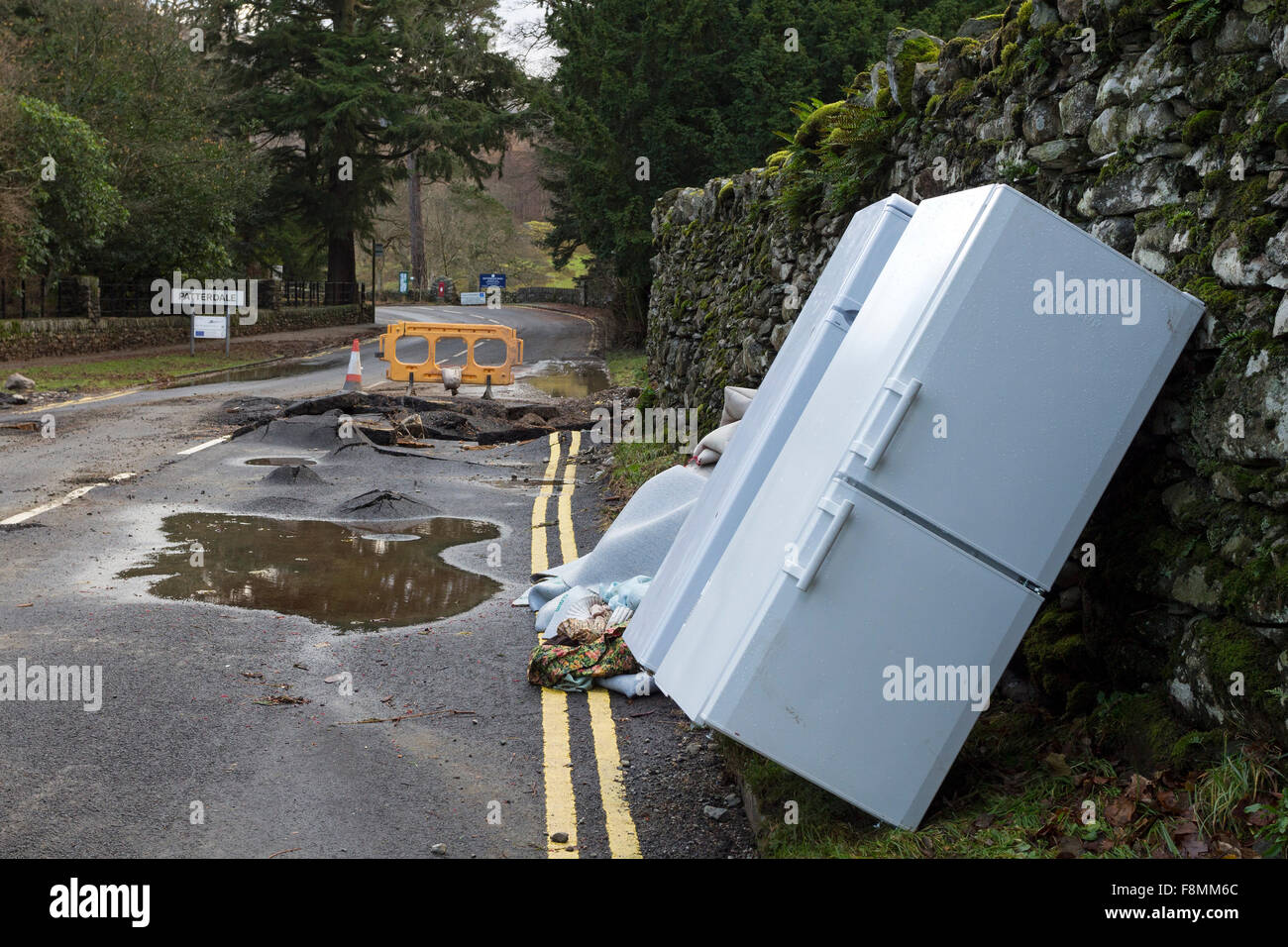 Glenridding, Cumbria, 10th December 2015. UK Weather.  Heavy overnight rain caused more flooding as the river running through the village overflowed again.  Rescue services were called in last night to help people to safety as people's possessions including Christmas decorations were washed down the road. Diggers were used this morning to try and dredge debris from the river in a bid to prevent further flooding.  In nearby Patterdale evidence of the power of the water from Storm Desmond could also be seen where floodwater had burst through the road surface. Credit:  David Forster/Alamy Live Ne Stock Photo