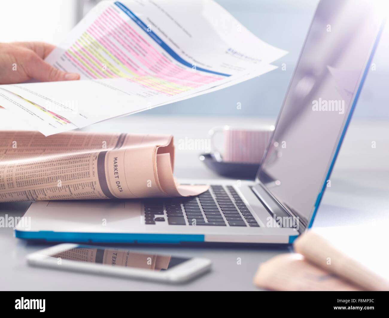 Man reviewing financial affairs using newspaper market data, investment statement and laptop Stock Photo