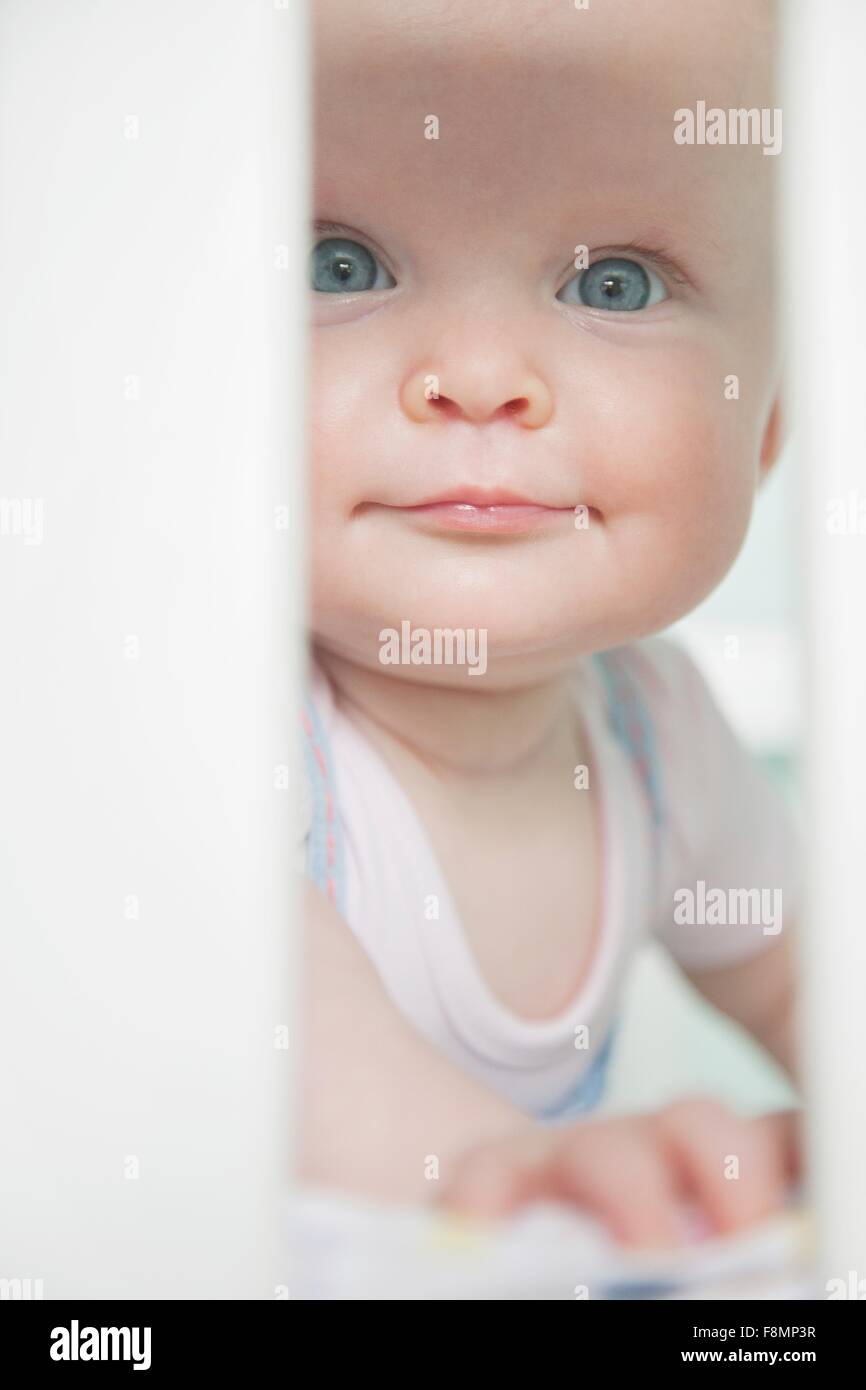 Portrait of baby girl looking through bars on cot Stock Photo Alamy