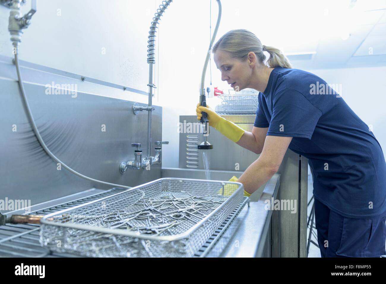 Worker cleaning surgical instruments in ultrasonic bath in surgical instrument factory Stock Photo