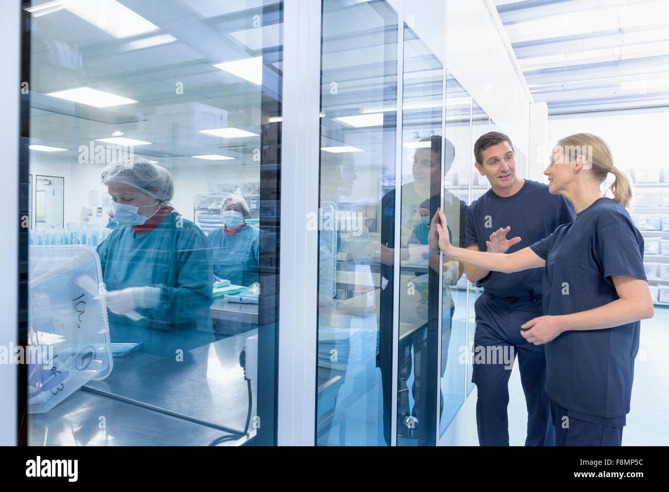 Workers in discussion outside clean room in surgical instrument factory Stock Photo