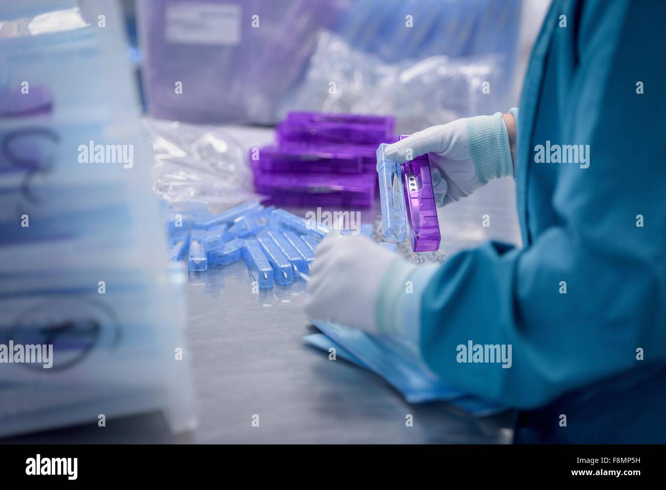 Worker packing surgical instruments in clean room of surgical instruments factory, close up