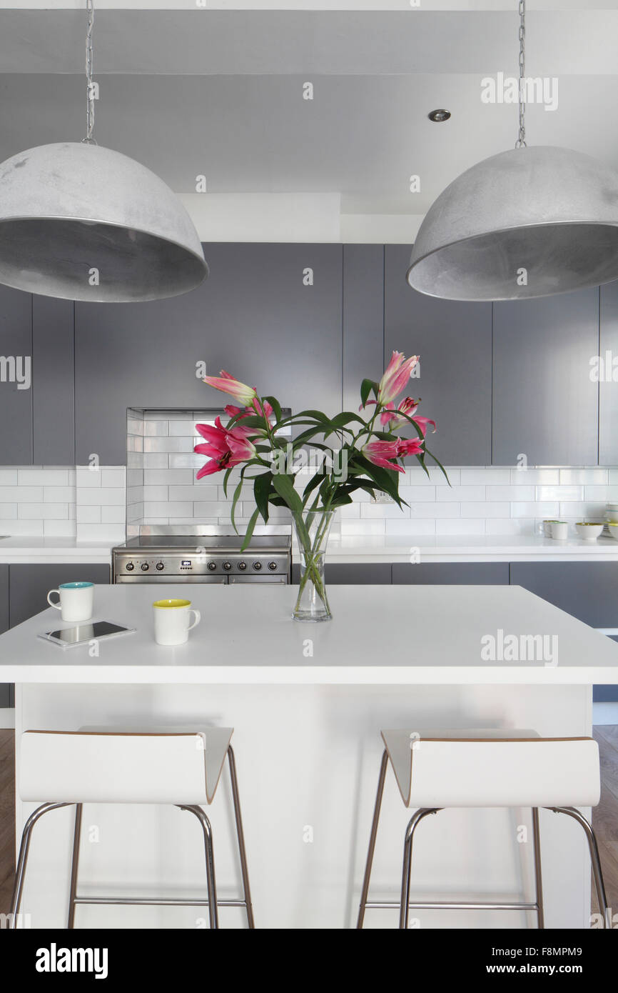 Island unit in kitchen with bar stools and industrial lights. Lights