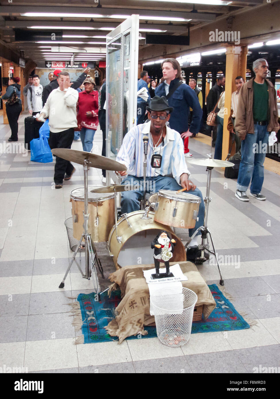 A front view of an African American playing the drums for money among