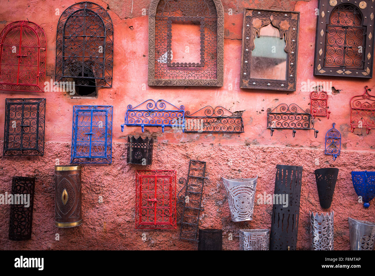 Metal coat hooks, lanterns and mirror frames hung on a red wall for sale in  the souks of Marrakesh Stock Photo - Alamy