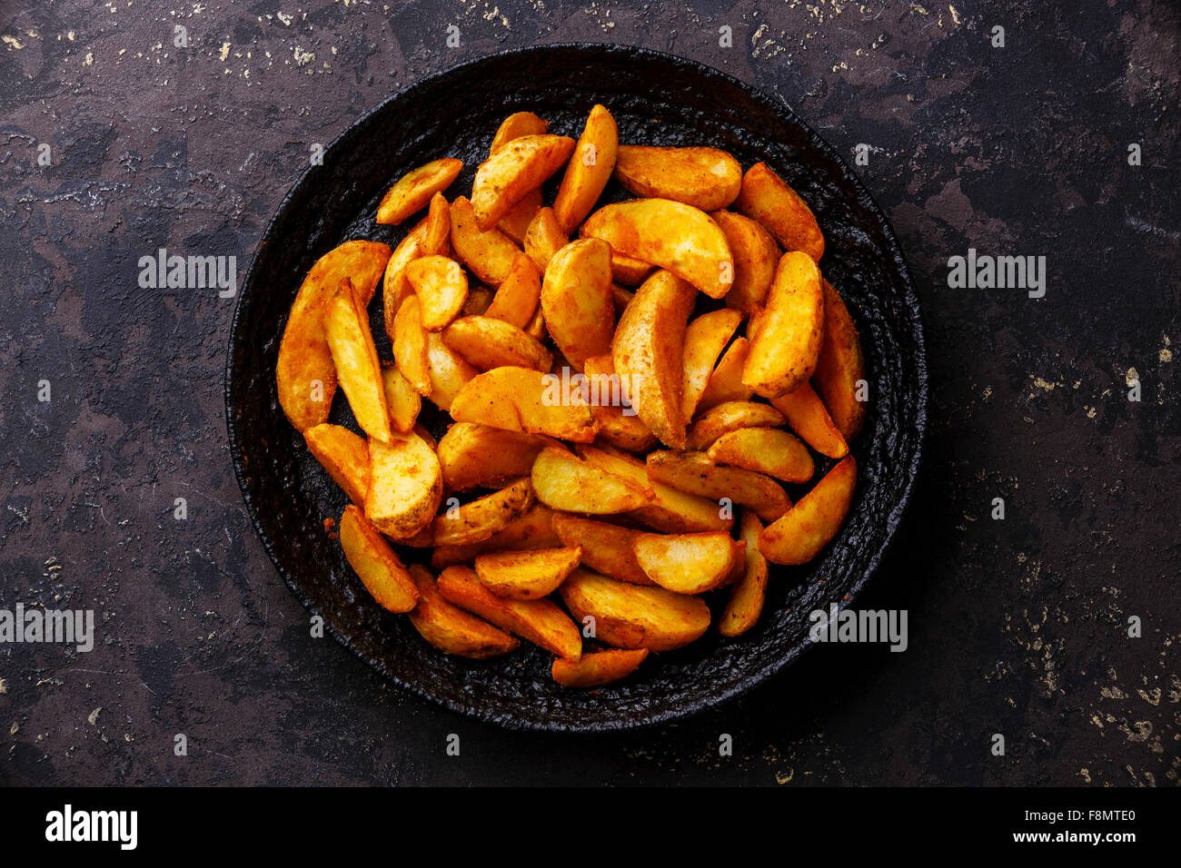 Fried potato wedges 'country-style' on black iron pan Stock Photo