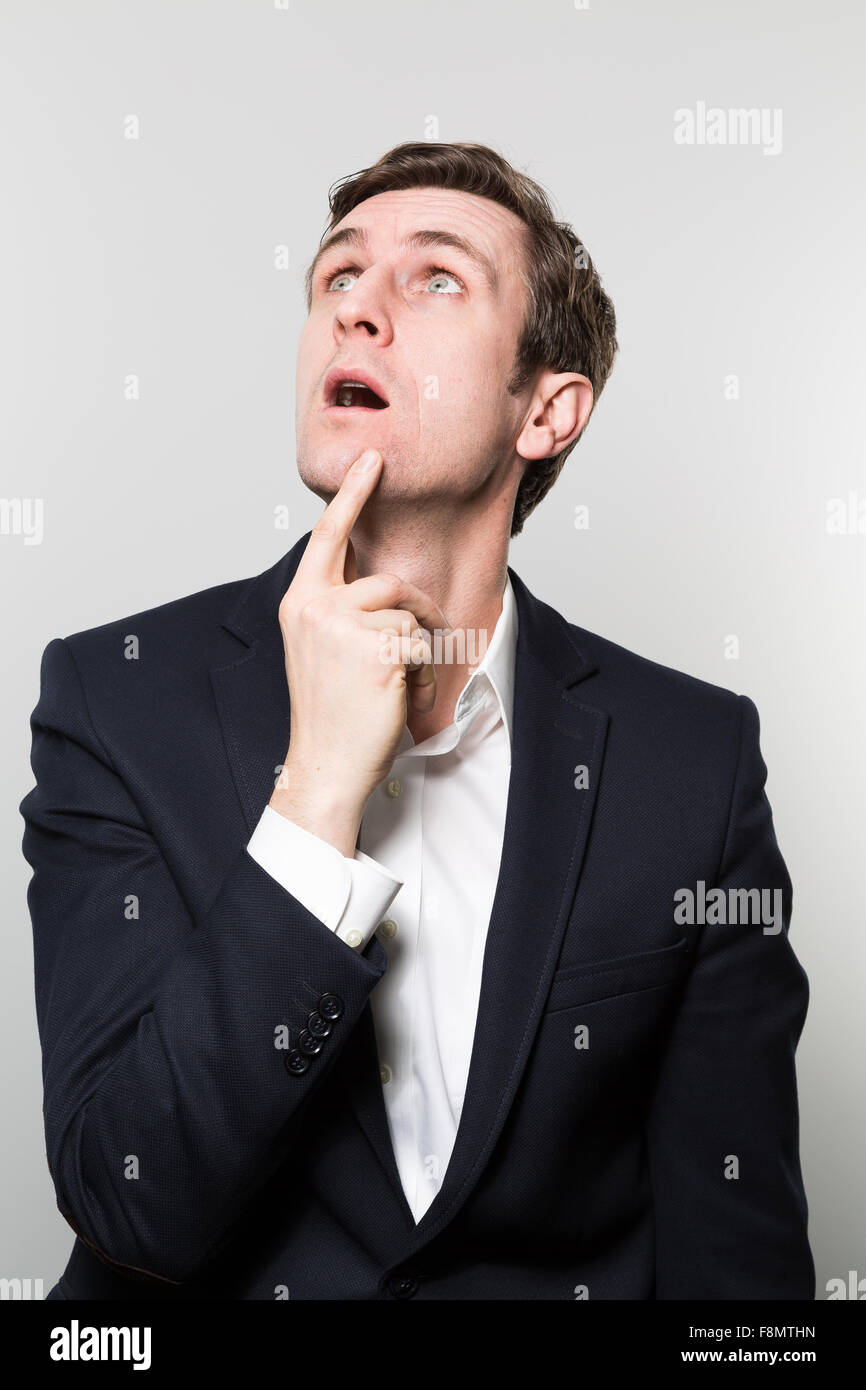 Blond-haired european businessman looks at the ceiling with a incredulous stare while in front of a gradient background Stock Photo