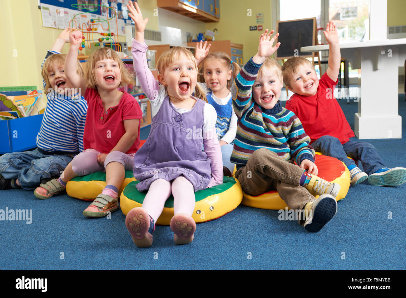 Group Of Pre School Children Answering Question In Classroom Stock Photo