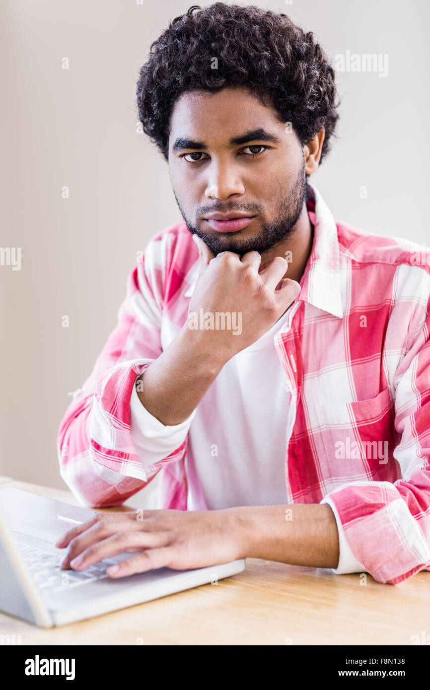 Thoughtful man using laptop looking at the camera Stock Photo