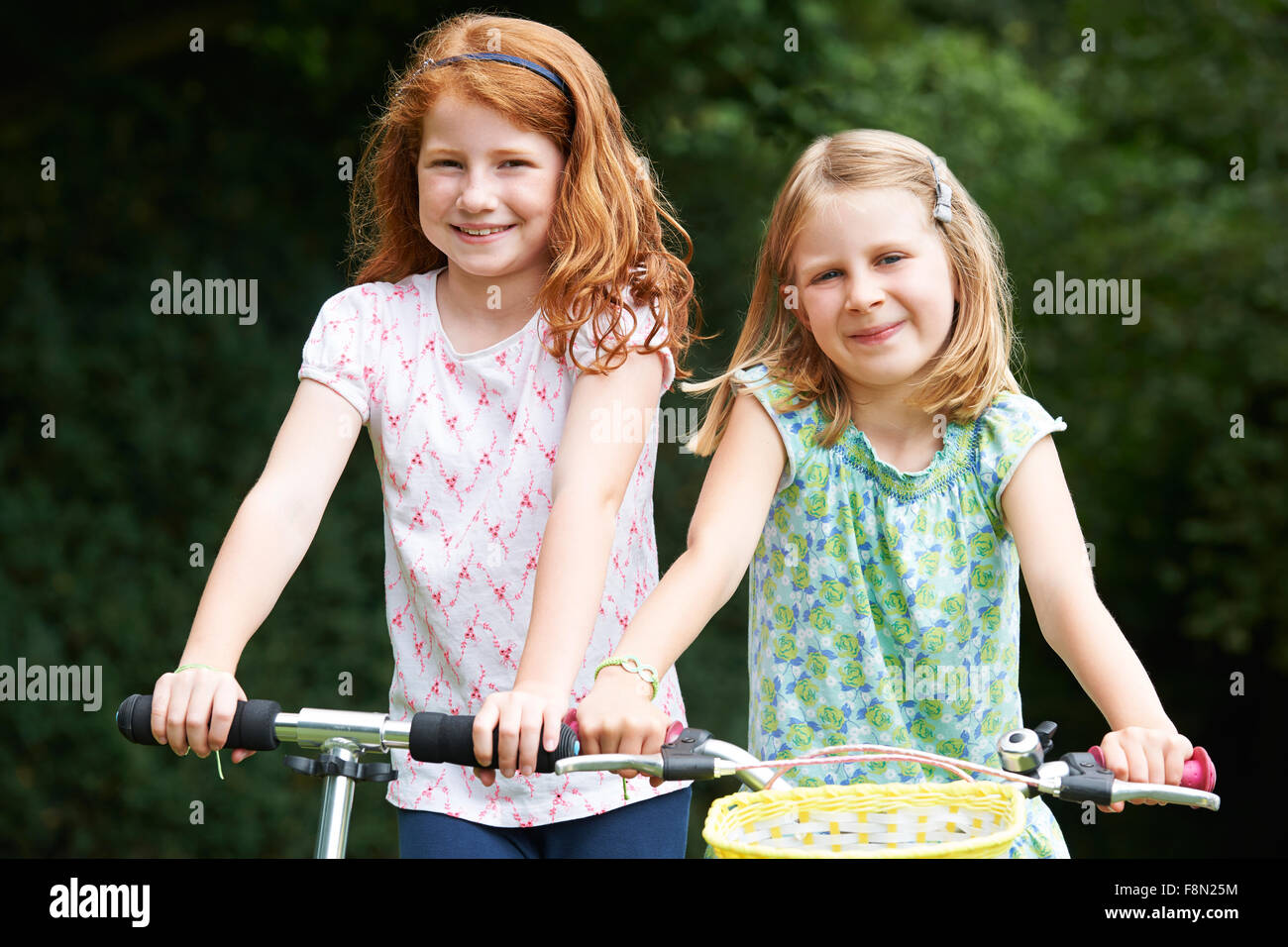 Two Girls Playing On Bike And Scooter Outdoors Stock Photo