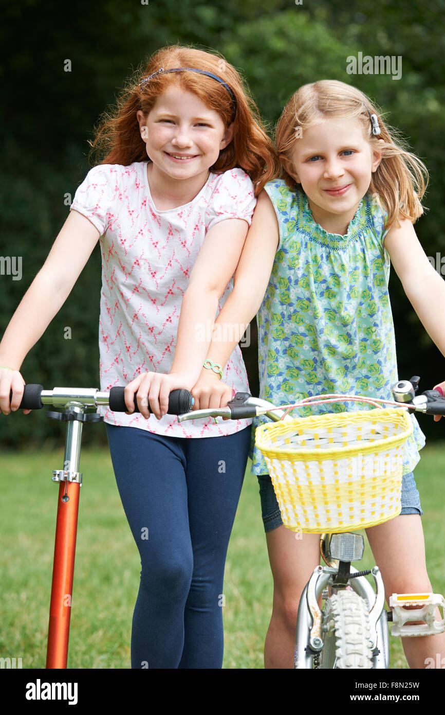 Two Girls Playing On Bike And Scooter Outdoors Stock Photo