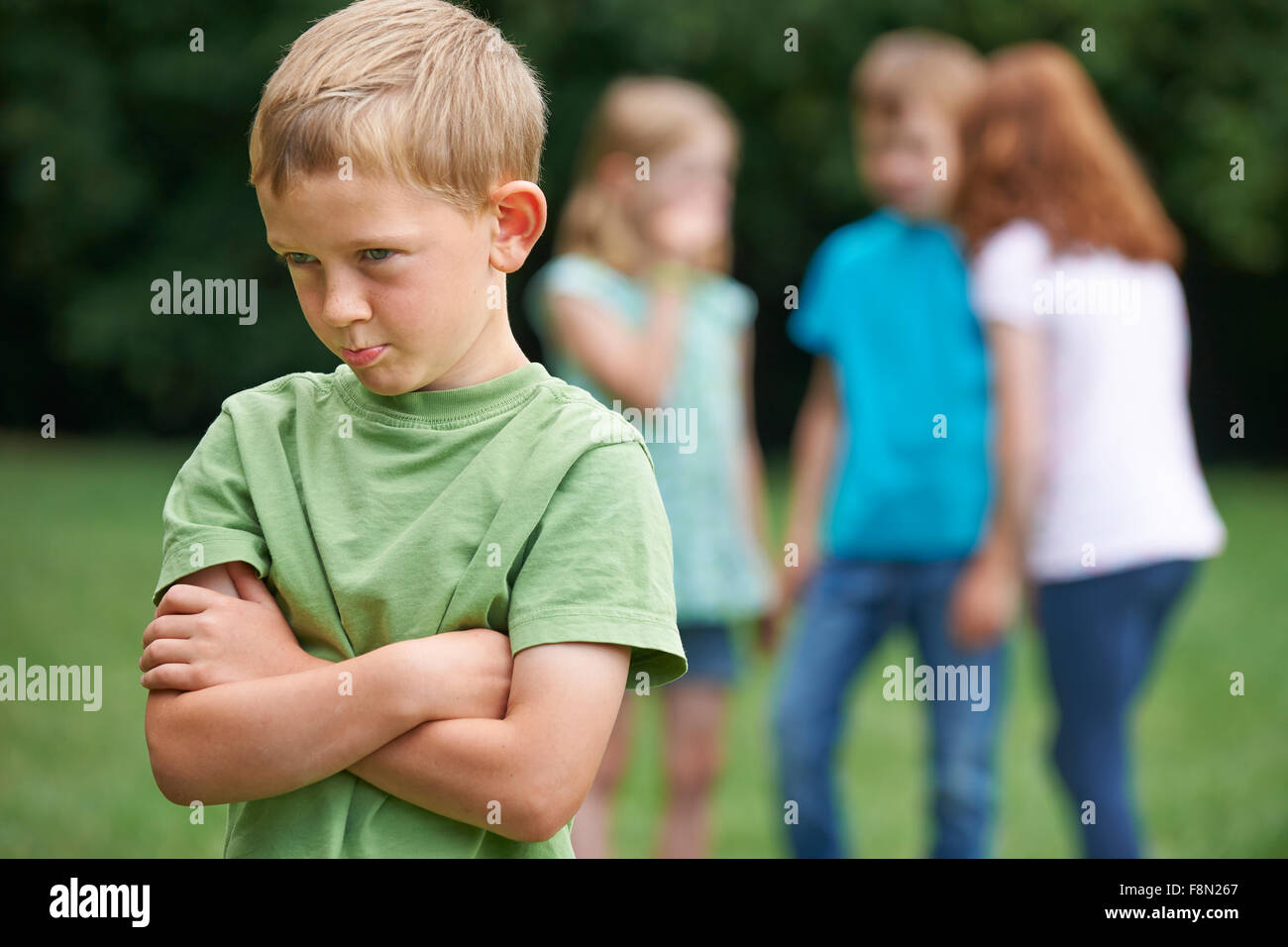 Unhappy Boy Being Gossiped About By Other Children Stock Photo