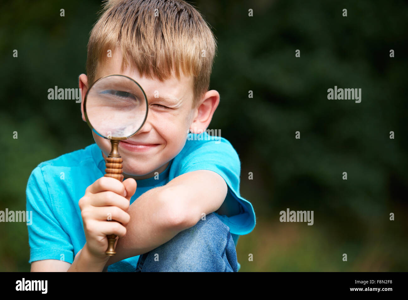 Boy Looking Through Magnifying Glass With Magnified Eye Stock Photo