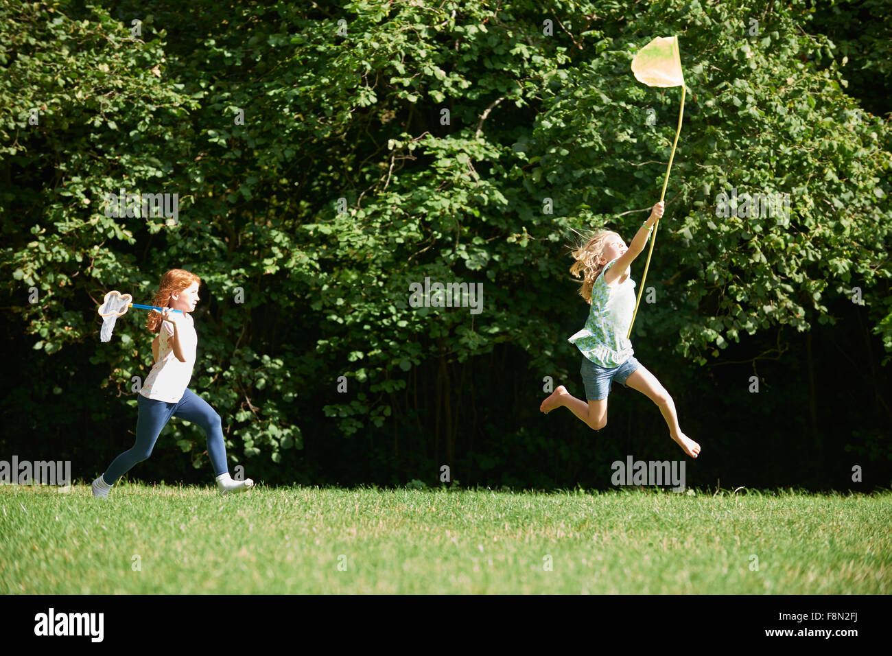 Two Girls Chasing Butterflies In Summer Field Stock Photo