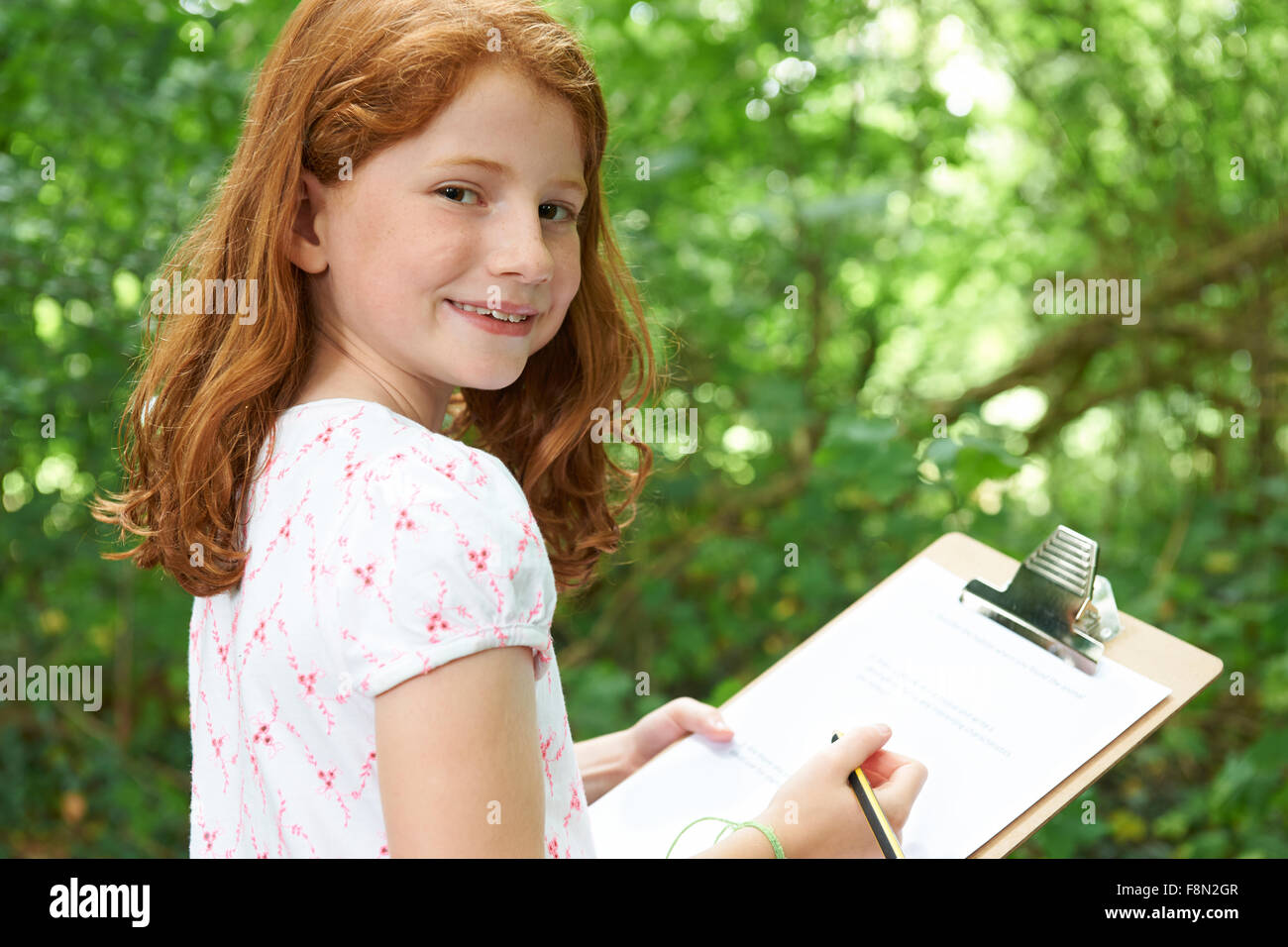Girl Making Notes On School Nature Field Trip Stock Photo