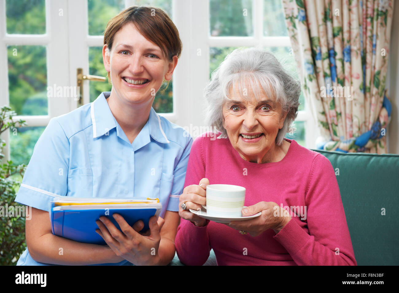Senior Woman Being Visited By Carer At Home Stock Photo