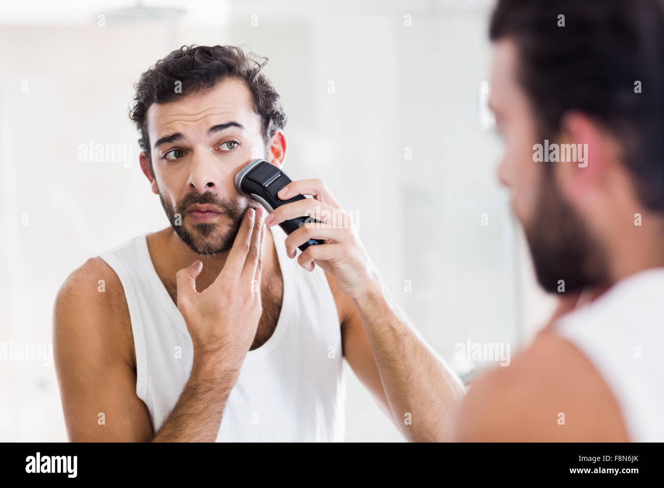 Reflection of concentrated man shaving with electric razor Stock Photo