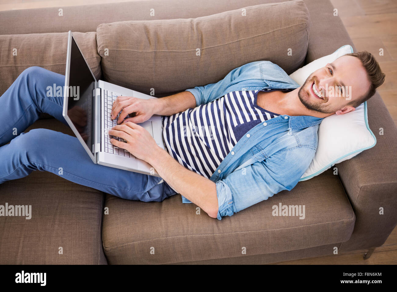 Handsome man using laptop on couch Stock Photo