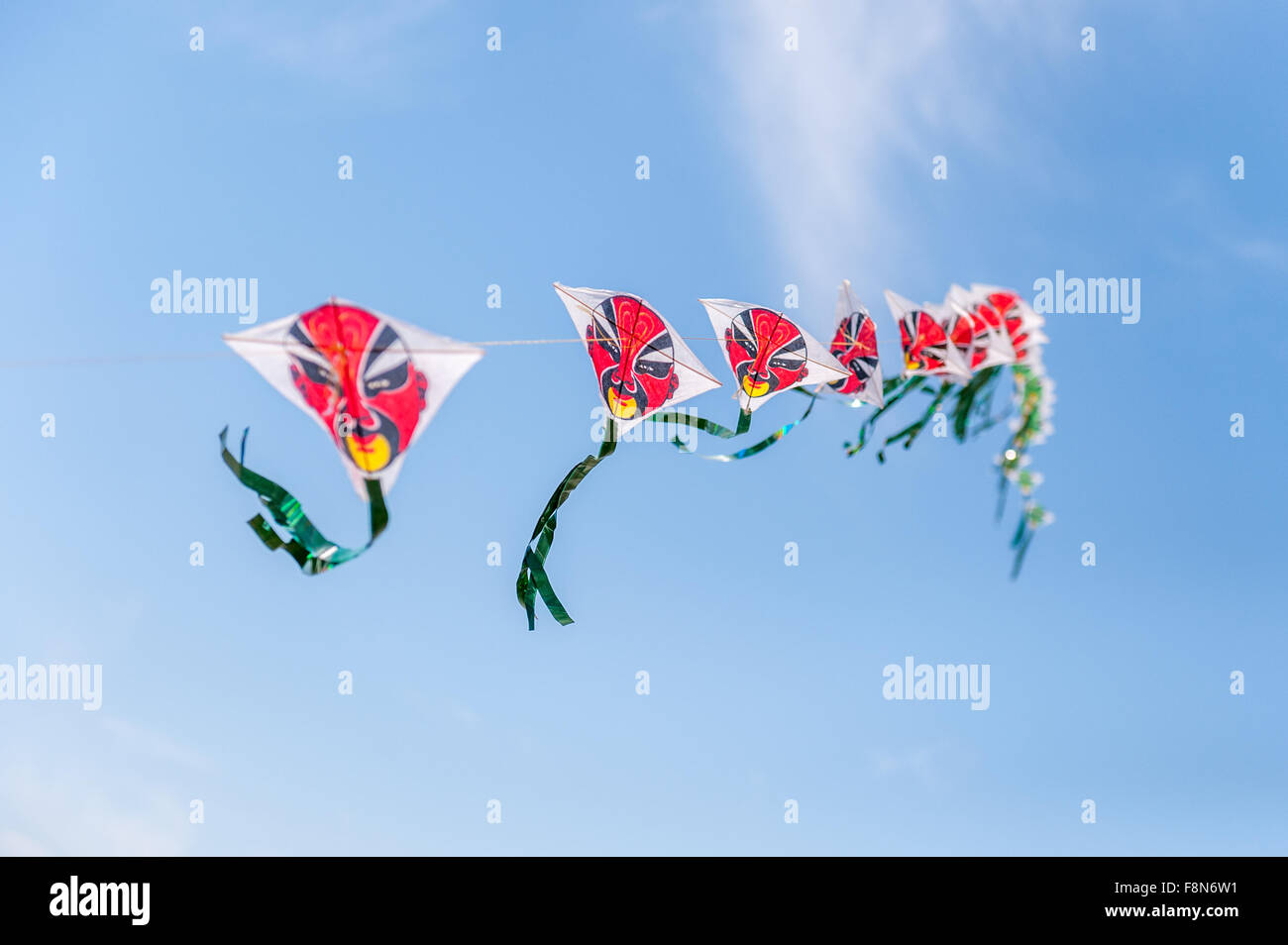 Multiple kites connected in sky with red faces Stock Photo