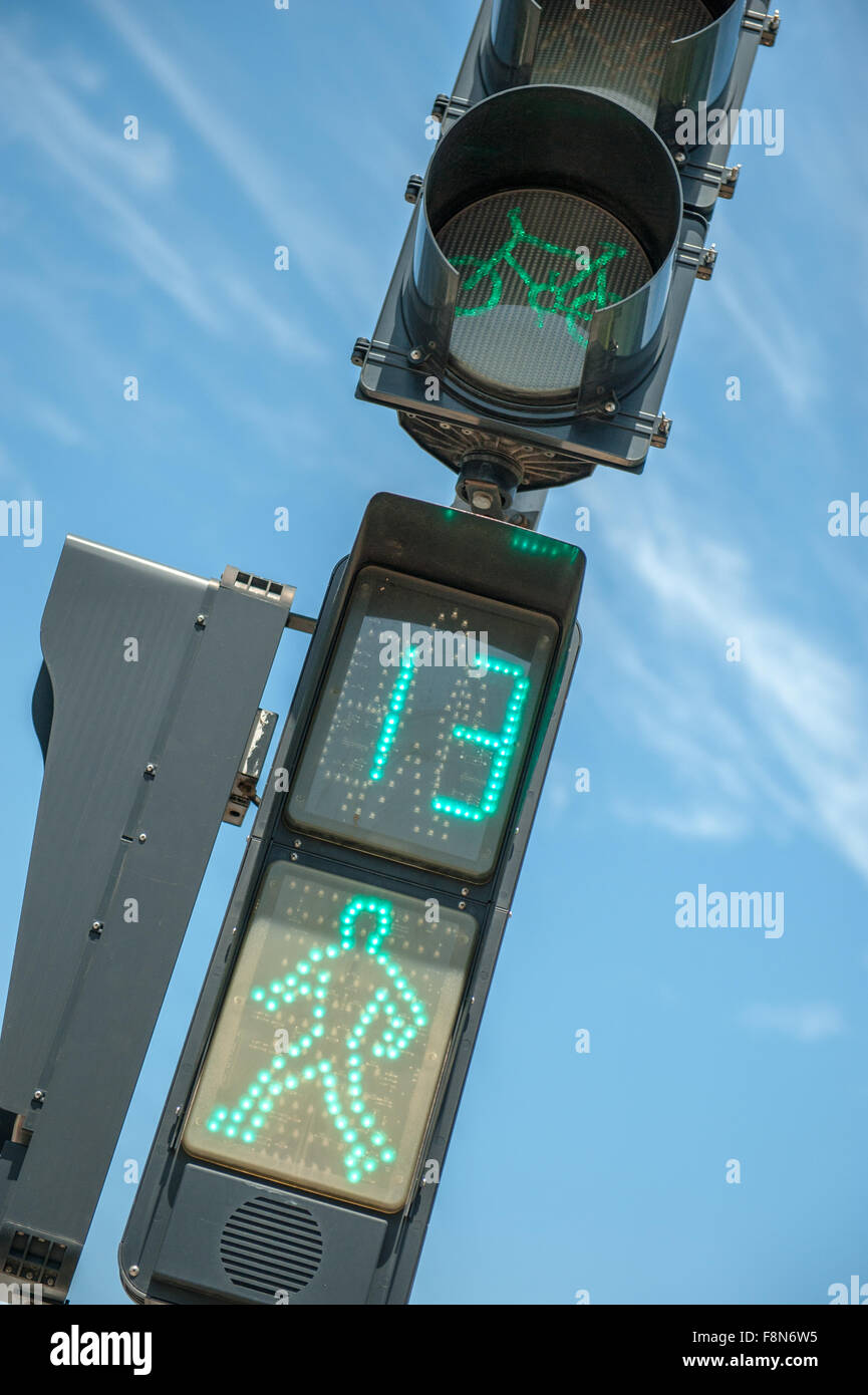 Pedestrian walking green lights against blue sky Stock Photo