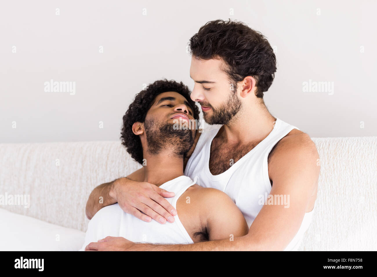 Happy gay couple cuddling on bed Stock Photo