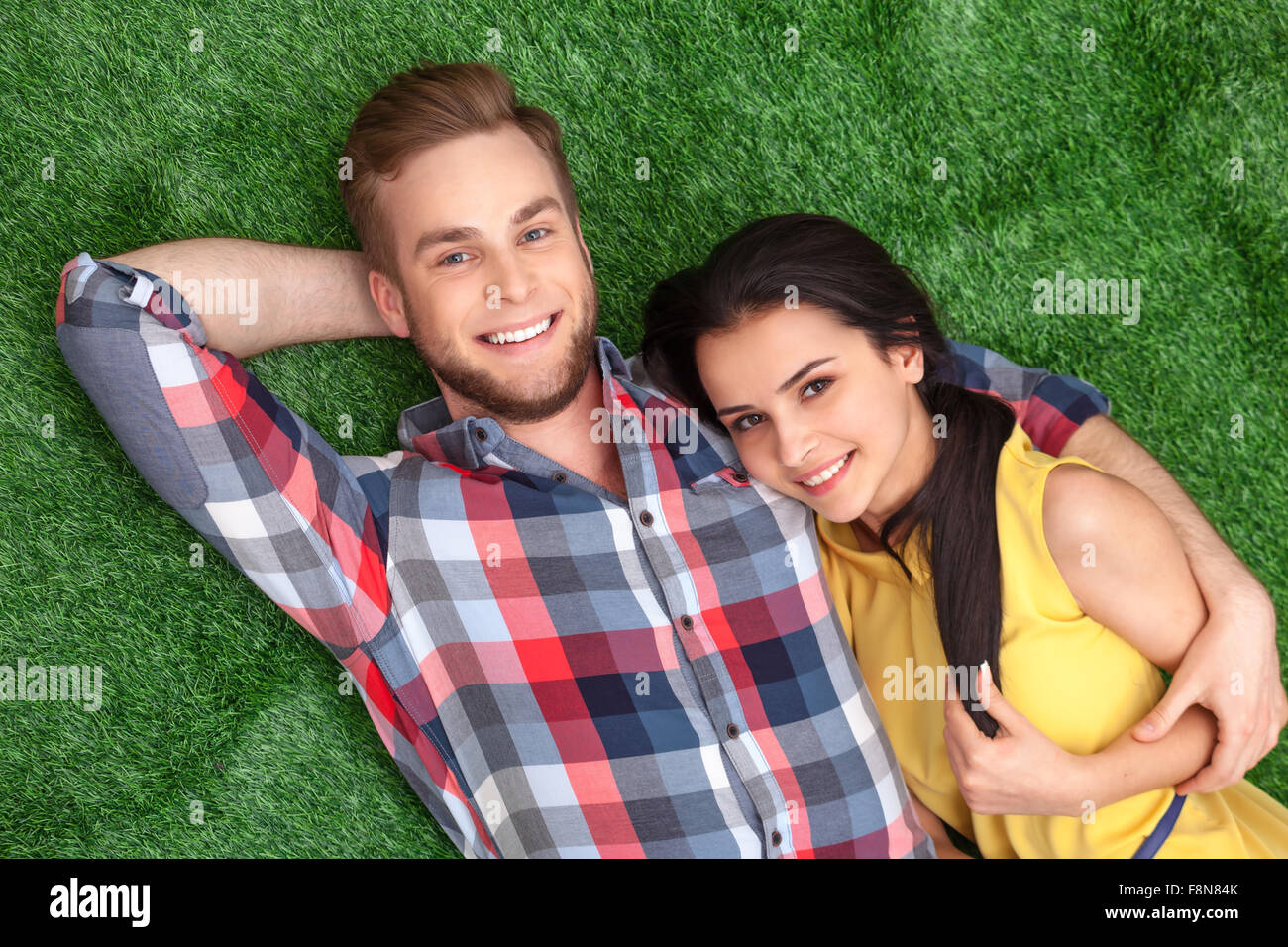Young couple lying on green grass Stock Photo - Alamy