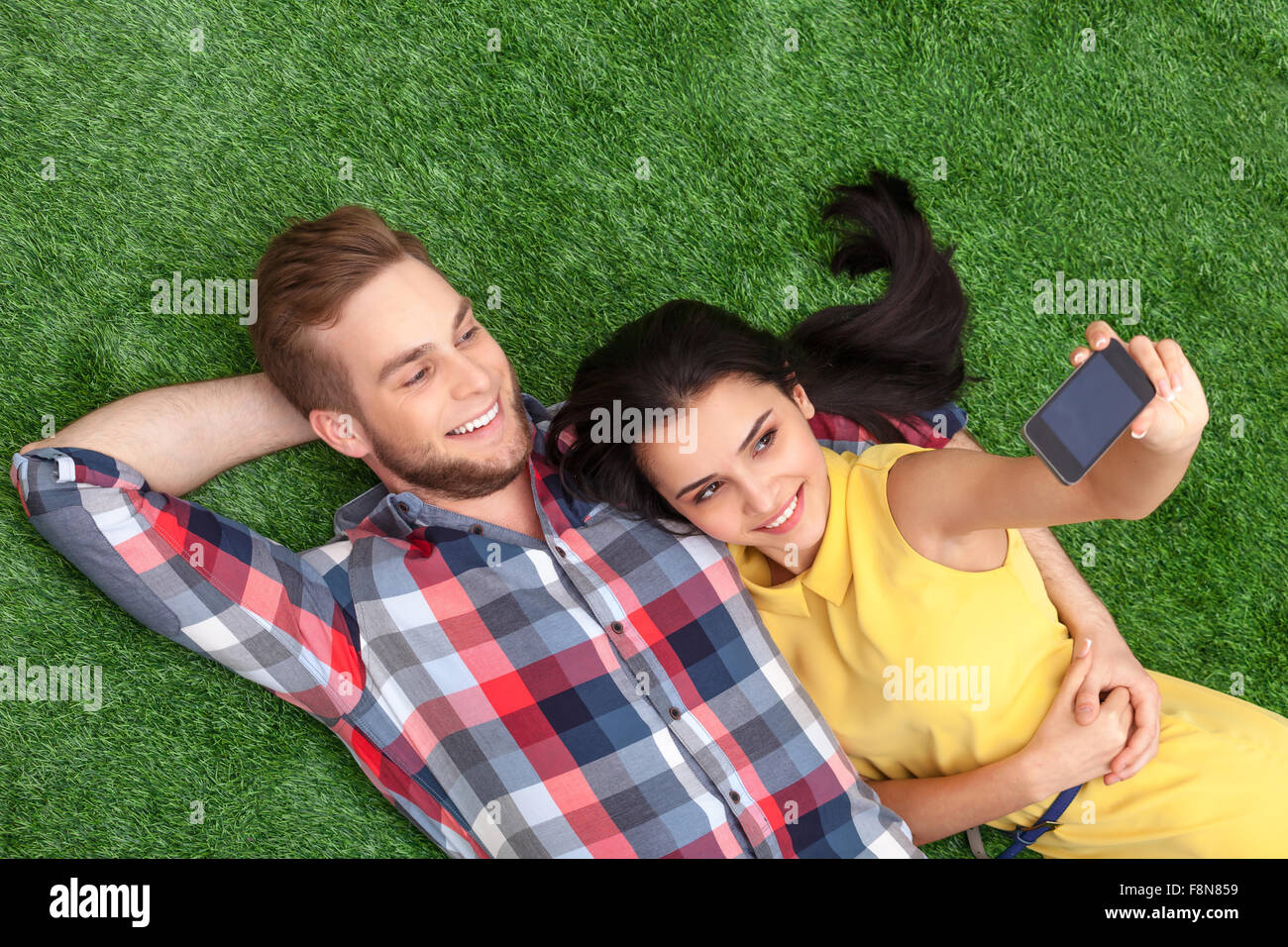 Young couple lying on green grass Stock Photo - Alamy