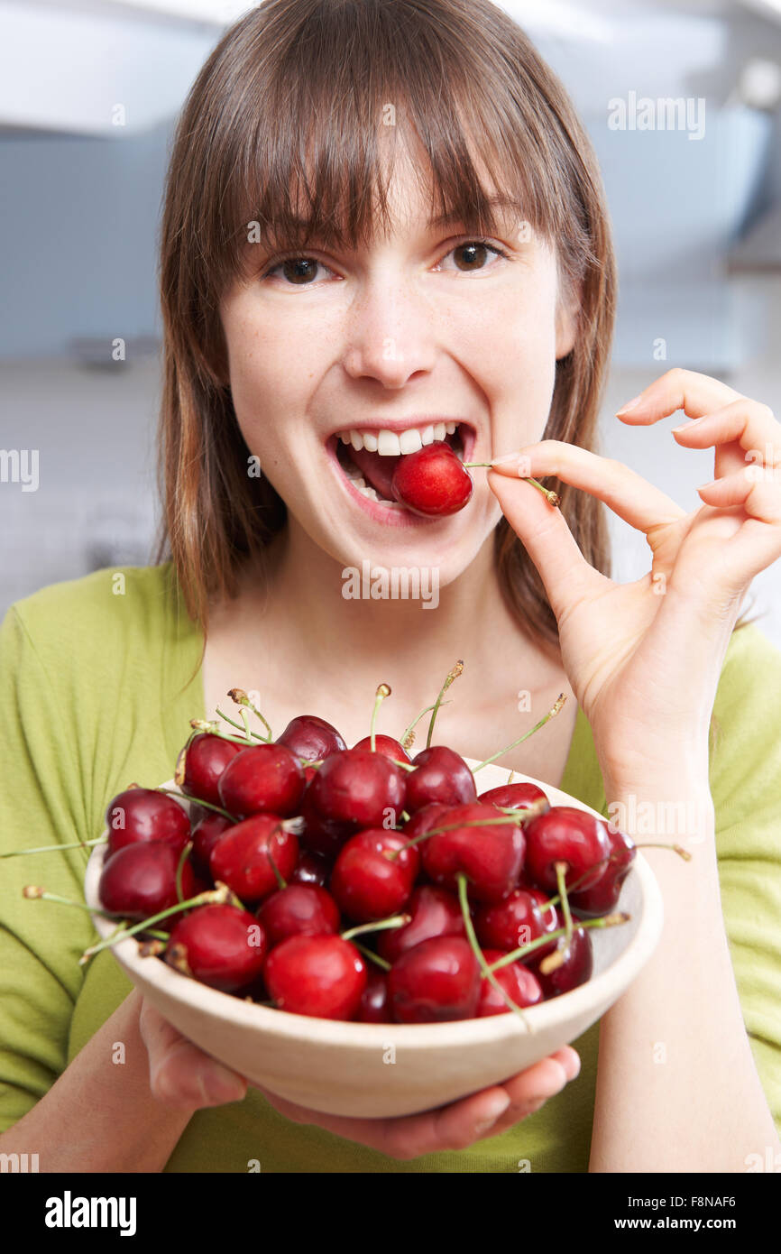 Young Woman Eating Cherries From Wooden Bowl Stock Photo Alamy